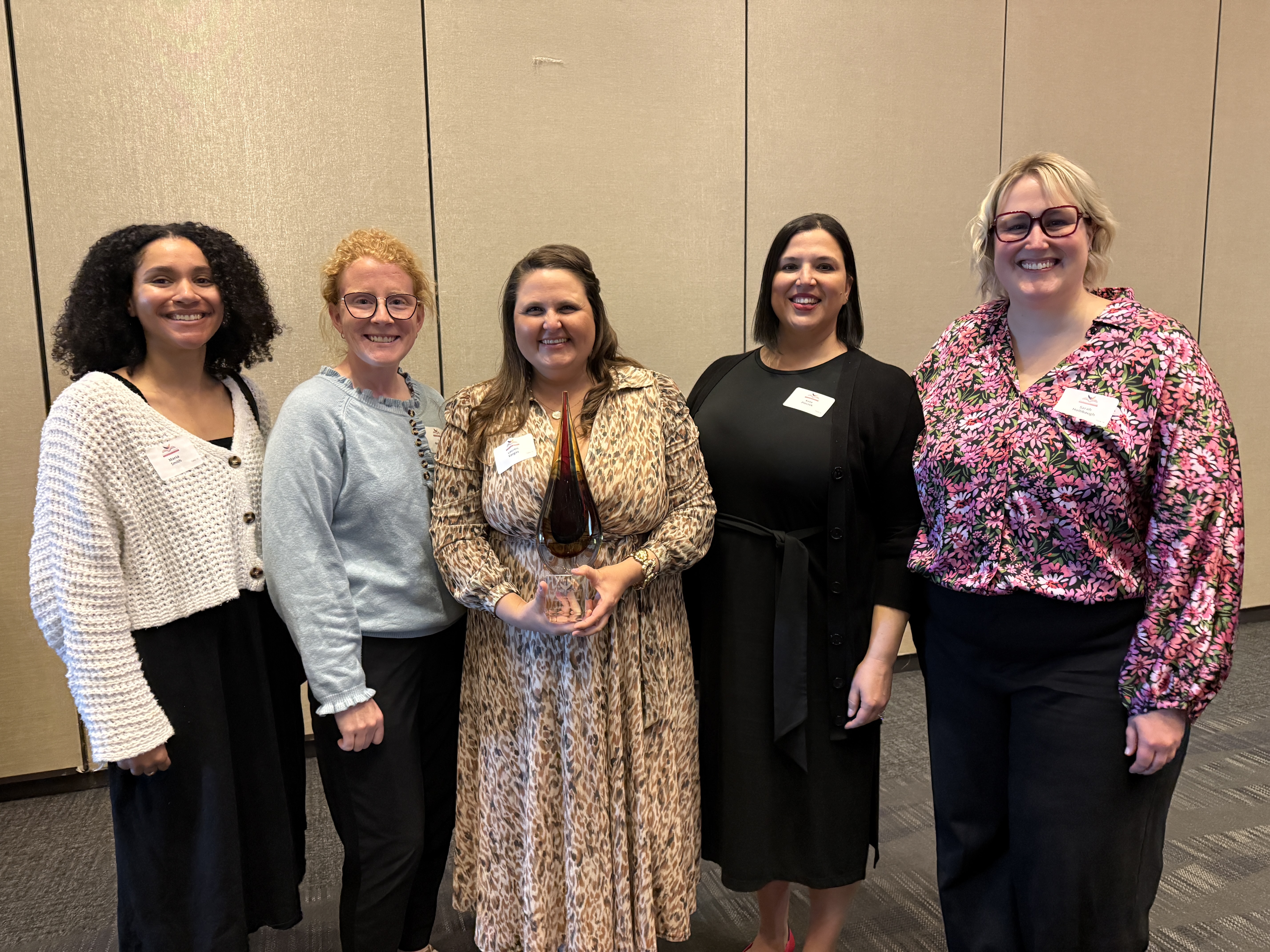 Maria, Liz, Lauren, Kate, and Sarah stand together as Lauren displays her award.